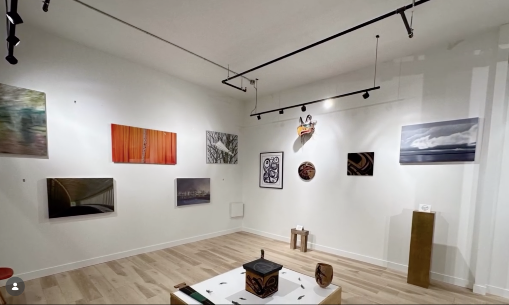 Art gallery with painting and photos hung on a white wall